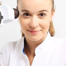 Woman in white coat using medical equipment.