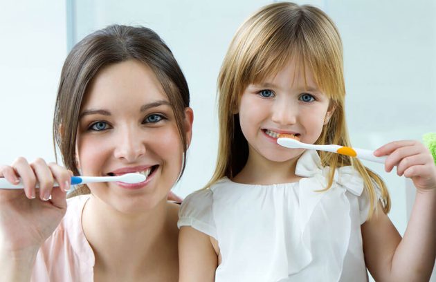 Mother and daughter brushing their teeth.