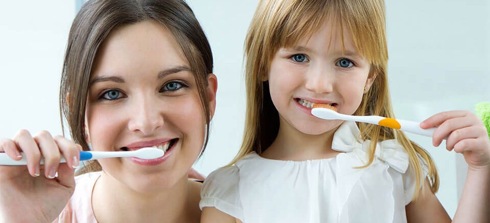 Mother and daughter brushing their teeth.