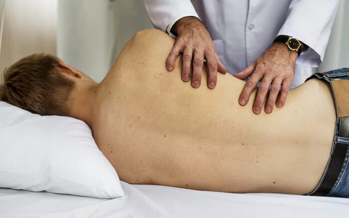 Doctor examining a patient's back.