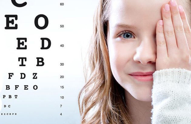 Young girl covering one eye with eye chart