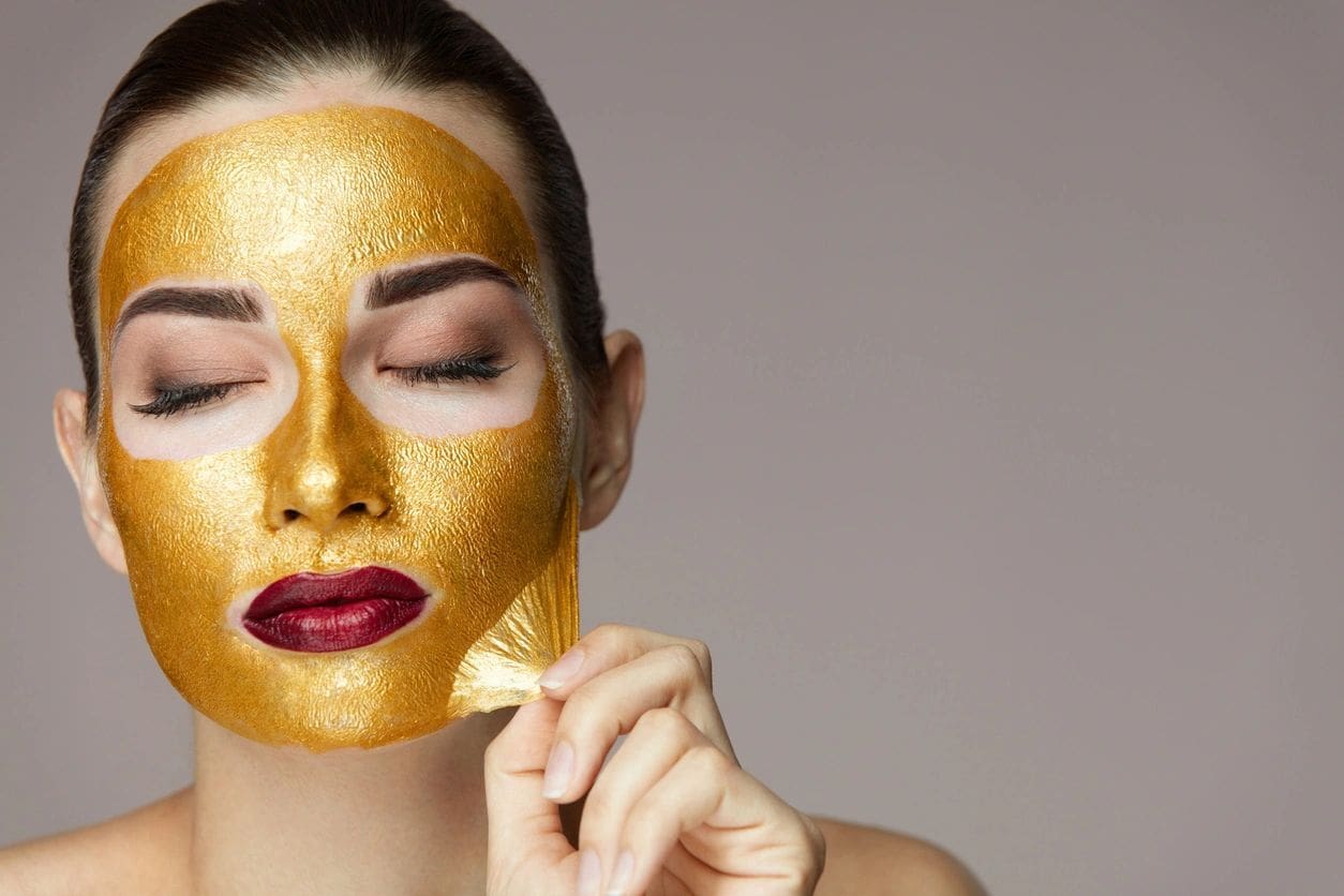 A woman with gold face mask on her face.