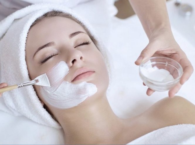 Woman receiving facial treatment with mask.